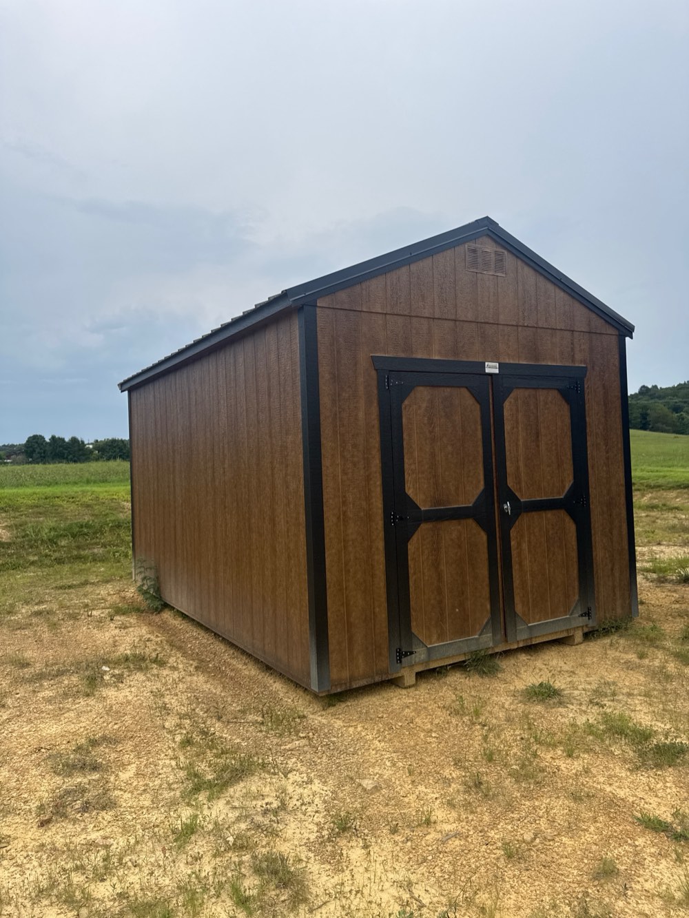Utility shed, 10 by 16, brown wood-grain siding with black double doors